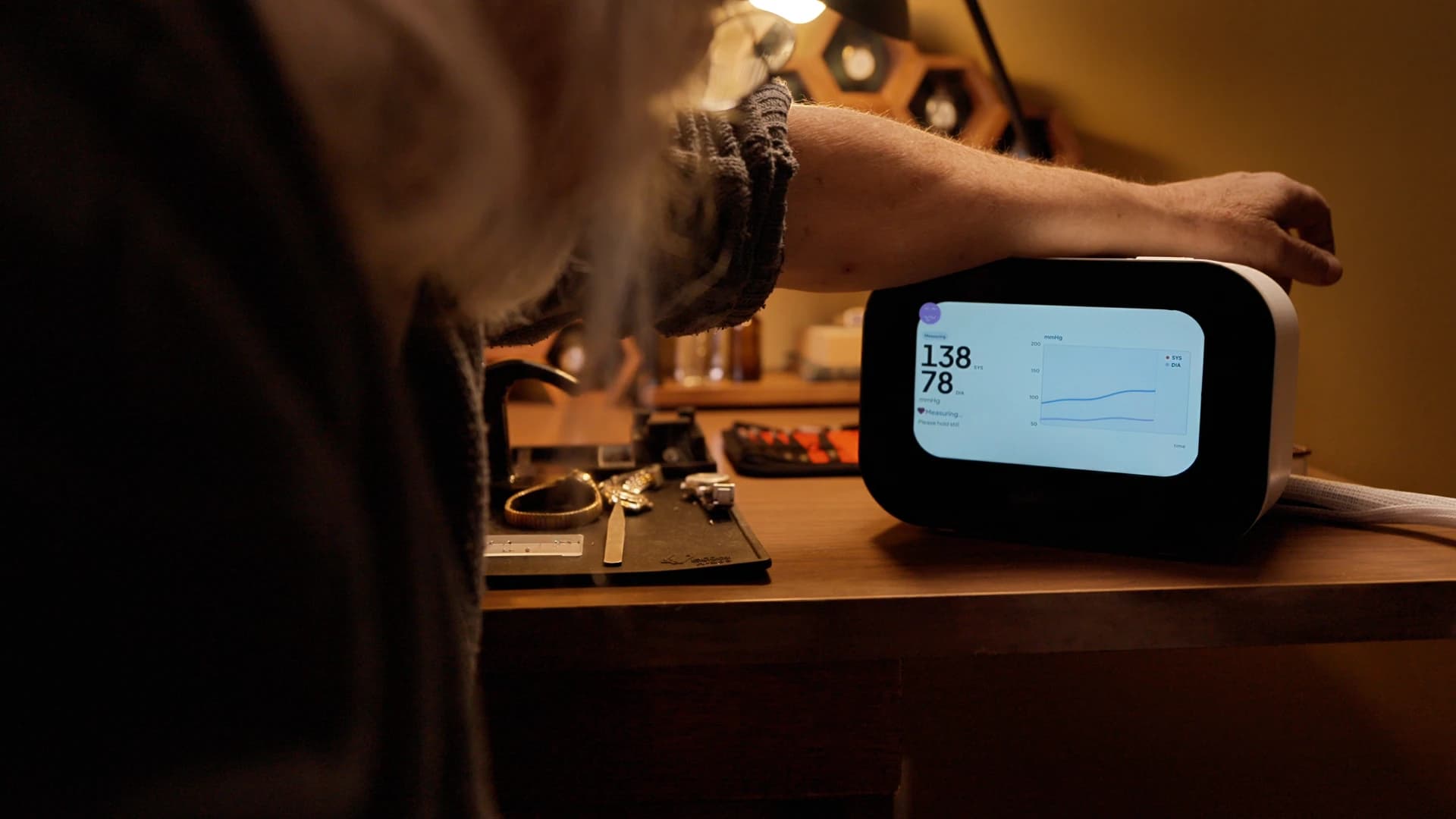 Person using a Rhem blood pressure monitor at home with live readings on screen