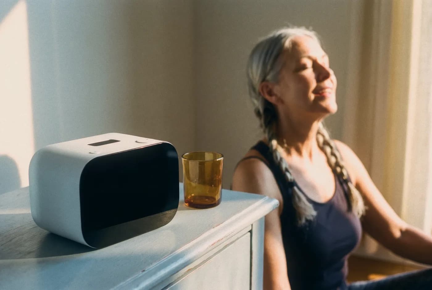 Rhem sobre una cómoda al sol de la mañana mientras una mujer se relaja al fondo