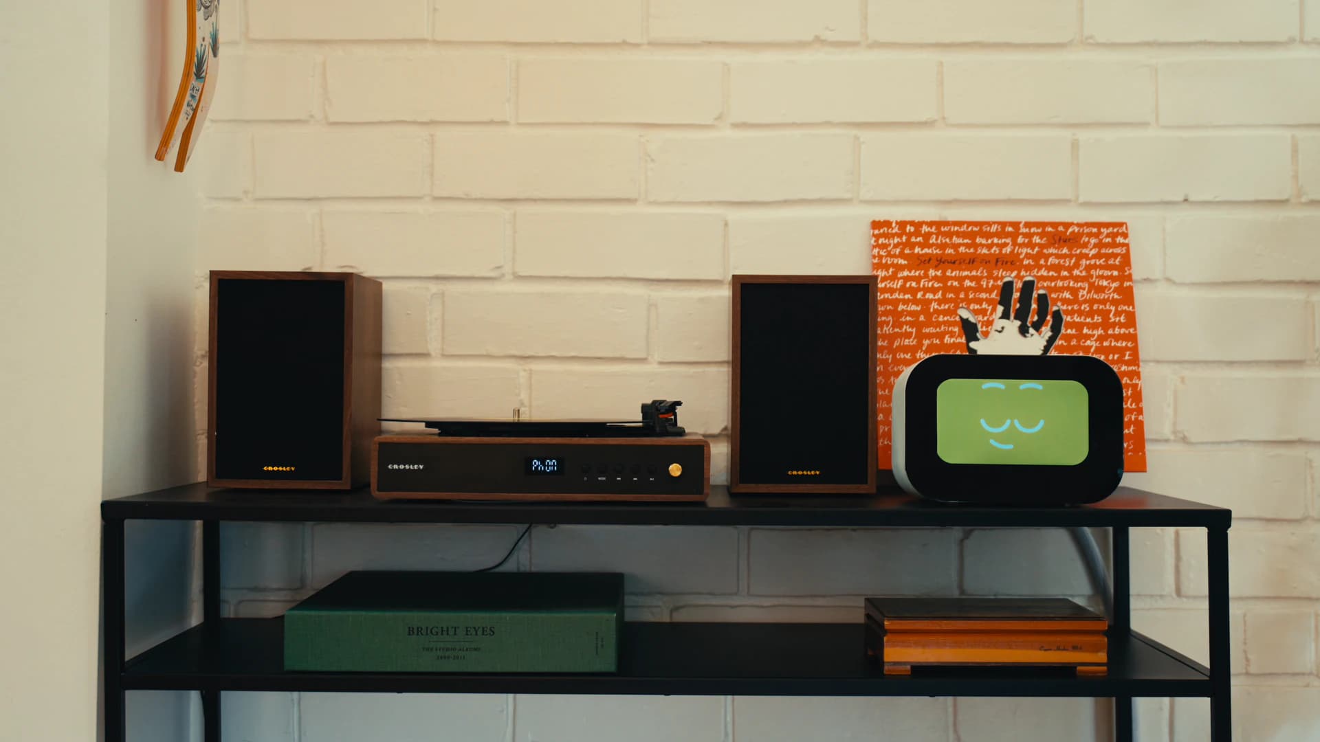 Rhem AI health robot on a media console with a turntable and speakers, showing a calm, content face.
